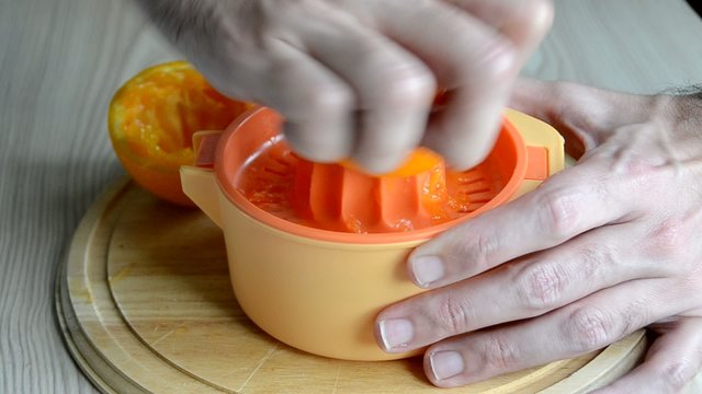 Un hombre preparando un zumo de naranja