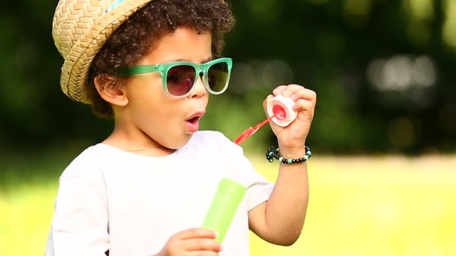 Small brazilian boy having fun blowing soap bubbles