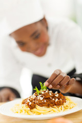 female african cook garnishing spaghetti