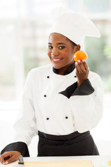 young female african chef holding tomato