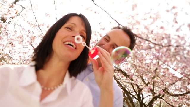 Mature woman blowing soap bubbles  with her husband