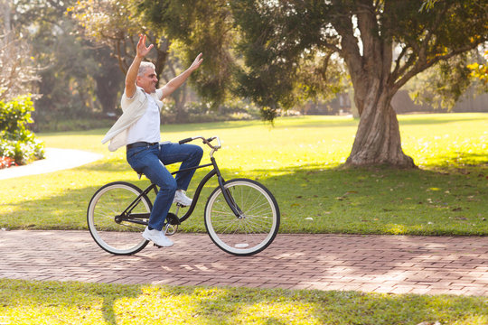 playful middle aged man riding a bike outdoors