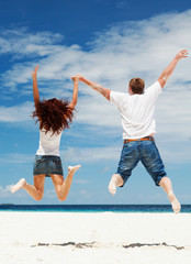 Happy couple jumping on the beach