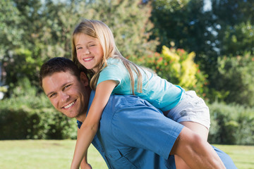 Fototapeta premium Daughter getting piggy back from dad