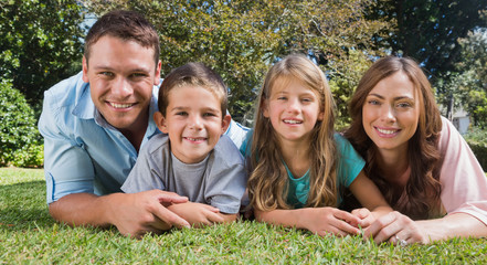 Fototapeta premium Smiling family lying on the grass