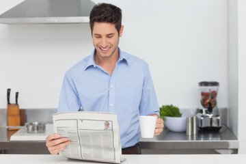 Man reading a newspaper in the kitchen