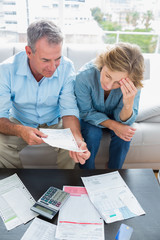 Couple sitting on their couch paying their bills