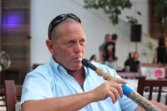 portrait of a man smoking a hookah waterpipe in a Turkish bazaar