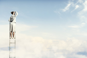 Businesswoman standing on ladder