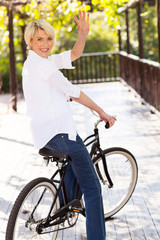 middle aged woman on a bike waving