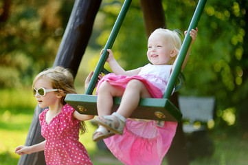 Two little sisters having fun on a swing