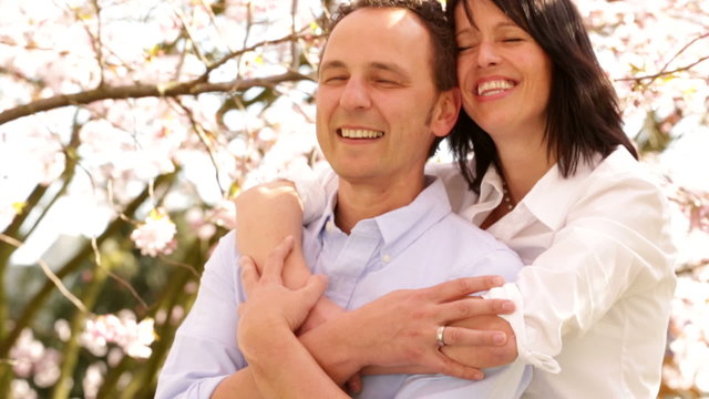 Happy best ager couple day dreaming amongst cherry trees