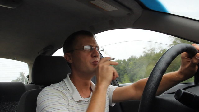 A man wearing glasses while driving.  