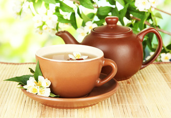 Cup of tea with jasmine, on bamboo mat, on bright background