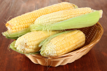 Fresh corn vegetable in wicker basket on wooden table