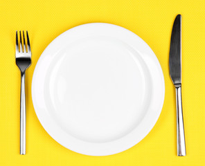 Knife, color plate and fork, on color background