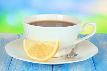 Cup of tea with lemon on table on blue background
