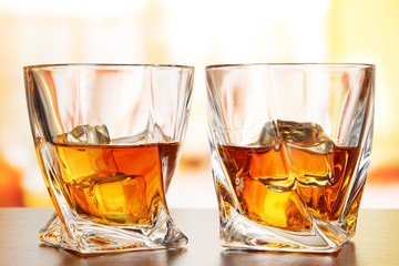 Glasses of whiskey, on bright background