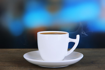 Fototapeta premium Cup of coffee on wooden table on bright background