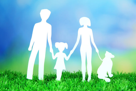 Family from paper on grass on bright background