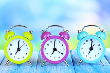 Colorful alarm clocks on table on blue background