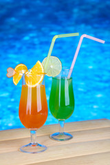 Tasty cocktails on swimming pool background