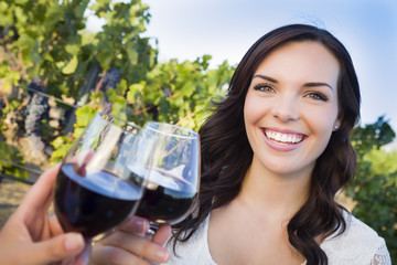 Young Woman Enjoying Glass of Wine in Vineyard With Friends