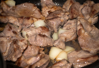 Fried meat with onion on pan.