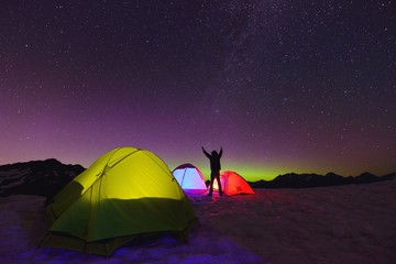 Aurora Borealis and tents on snow mountain