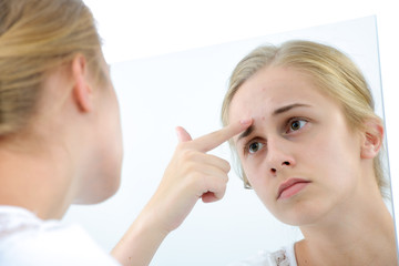 Teenager checking her face for pimple in the mirror