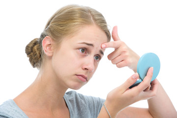 Teenage girl checking her face for pimple in the mirror