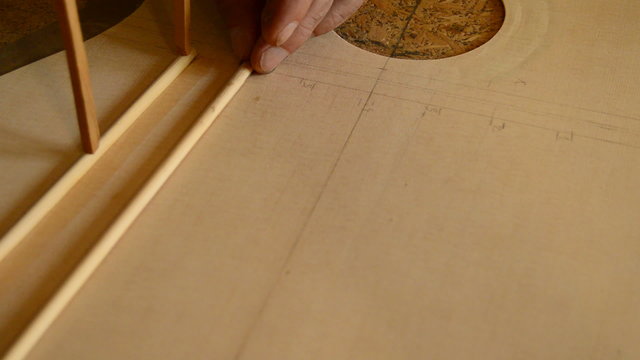 Luthier puts a rod in the harmonic cover of a guitar