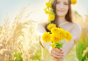 Pretty girl holding bouquet in the sunny summer grass field