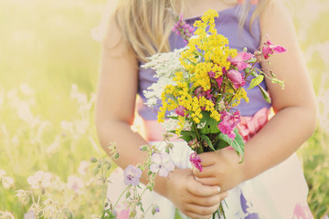 Little girl with flowers on grassy field