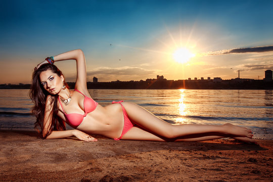 woman lies on beach at sunset