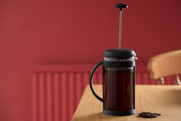 Freshly brewed coffee on table in red room in a cafetiere