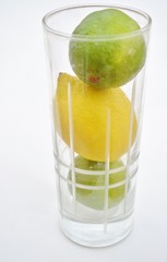 lemons and limes in a glass on a white background.