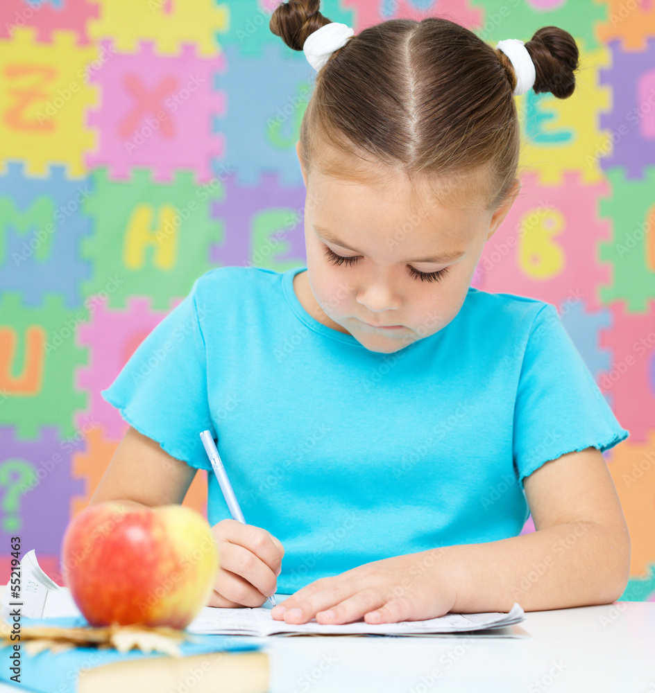 Wall mural little girl is writing using a pen