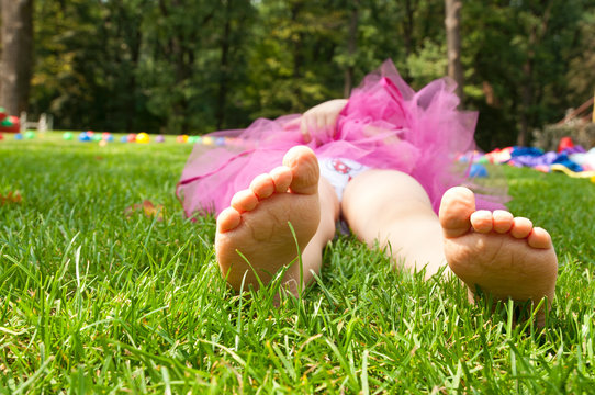 happy little girl lying on green grass