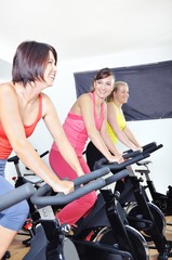 Fototapeta na wymiar Beautiful women doing exercise in a spinning class at gym