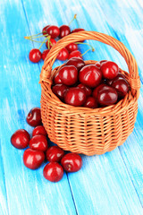 Cherry berries in wicker basket on wooden table close-up