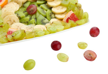 Assortment of sliced fruits on plate, isolated on white