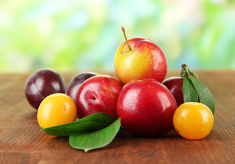 Ripe plums on wooden table on natural background