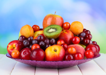 Assortment of juicy fruits on wooden table, on bright