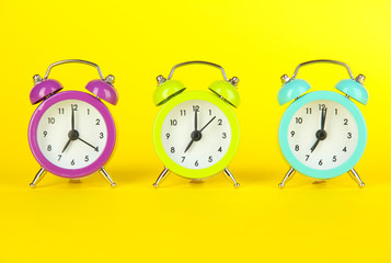 Colorful alarm clock on yellow background