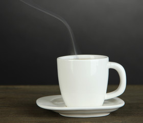 Cup of coffee on wooden table on black background