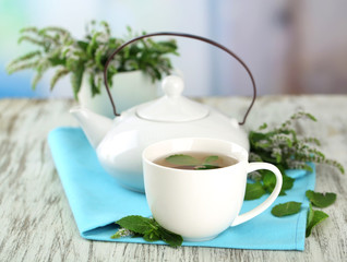 Teapot and cup of herbal tea with fresh mint flowers