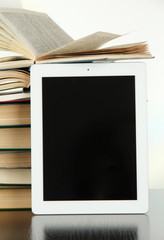Tablet and books on light background