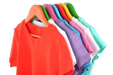 Different shirts on colorful hangers on white background