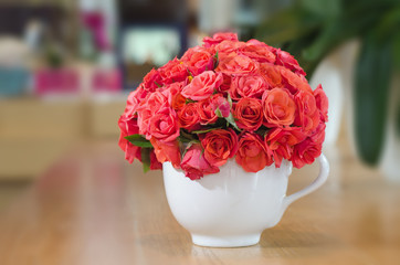 Beautiful red roses in vase on wooden table 